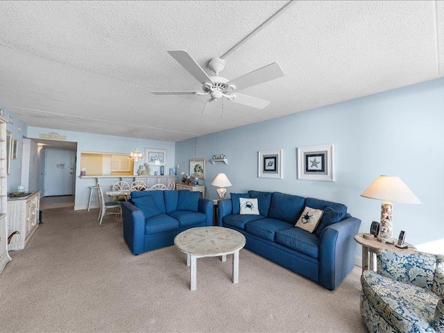 carpeted living room featuring a textured ceiling and ceiling fan with notable chandelier