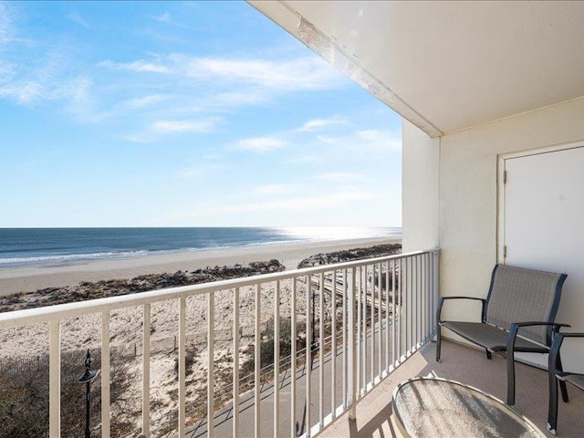 balcony with a water view and a view of the beach