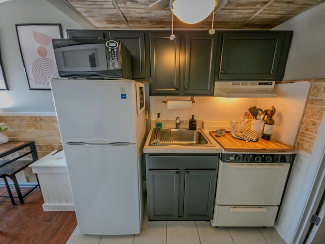 kitchen featuring freestanding refrigerator, exhaust hood, a sink, and green cabinetry