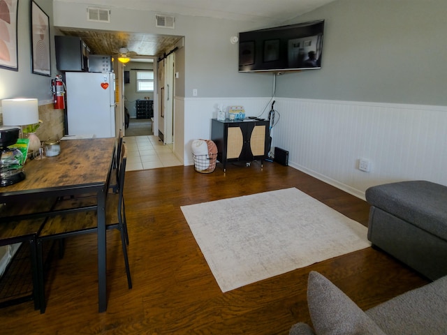 living area featuring a wainscoted wall, visible vents, and wood finished floors