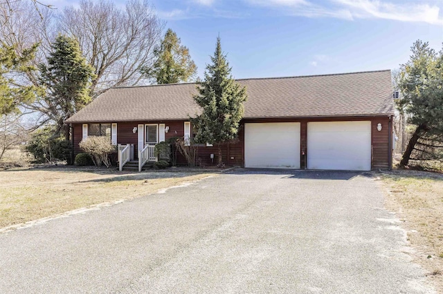 ranch-style home featuring a garage and a shingled roof