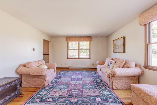 living room featuring a wealth of natural light, a baseboard heating unit, and light wood finished floors