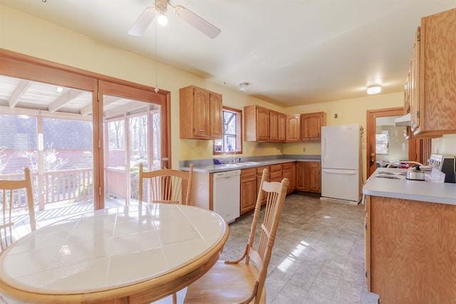 kitchen with light floors, light countertops, white appliances, a ceiling fan, and a sink