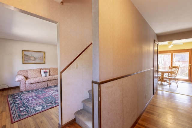 stairs with wood-type flooring and ceiling fan