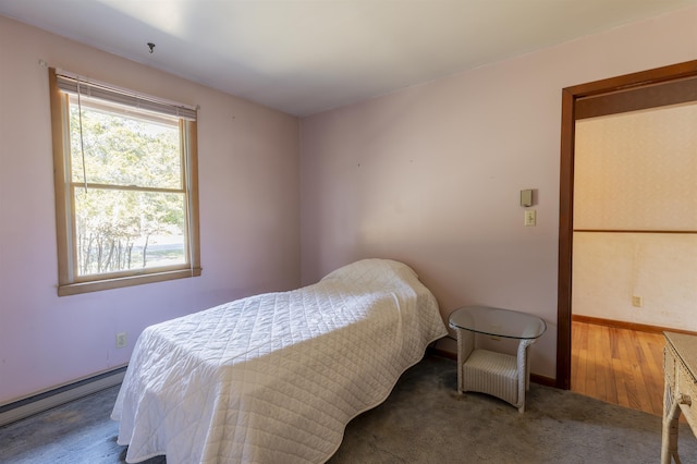 bedroom featuring a baseboard radiator, baseboards, and wood finished floors