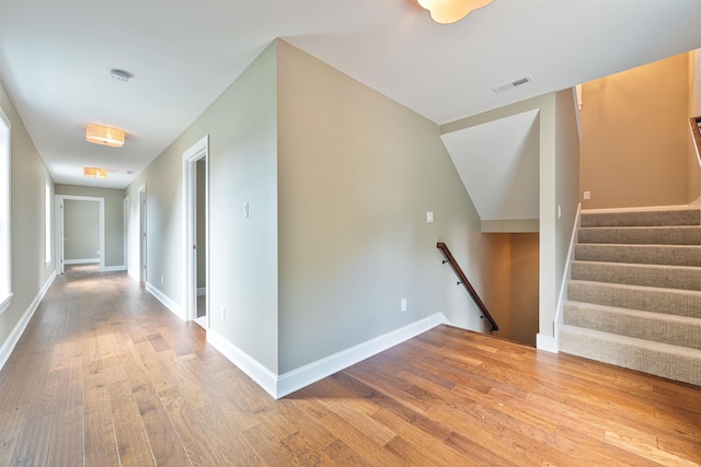 hallway featuring wood-type flooring and vaulted ceiling