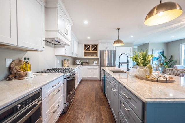 kitchen with sink, light stone countertops, appliances with stainless steel finishes, decorative light fixtures, and white cabinetry