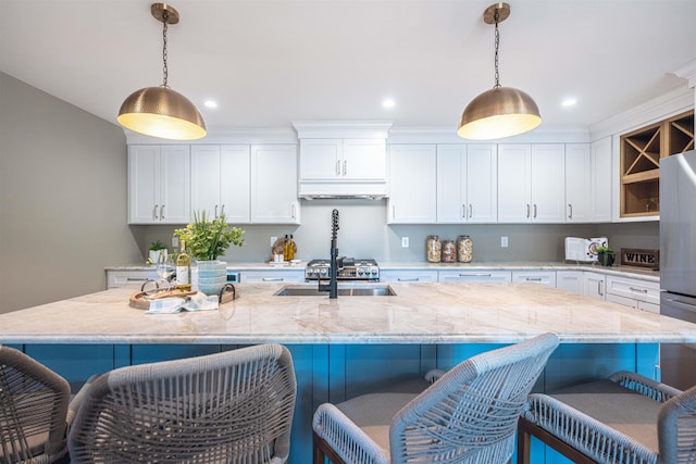 kitchen featuring a breakfast bar, white cabinetry, pendant lighting, and a spacious island