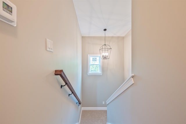 stairs with carpet flooring and an inviting chandelier