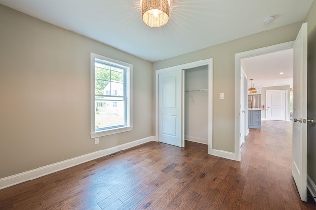 unfurnished bedroom featuring dark hardwood / wood-style flooring and a closet