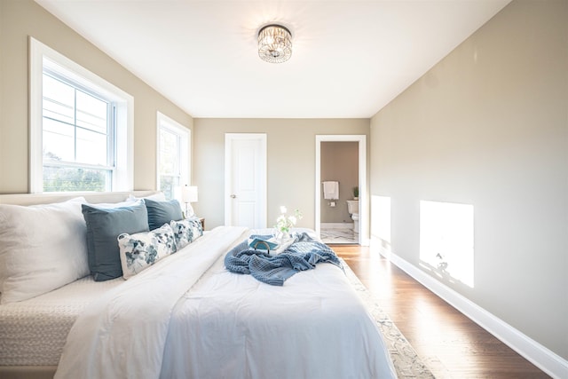 bedroom featuring ensuite bath and hardwood / wood-style flooring