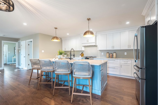 kitchen with decorative light fixtures, white cabinetry, a kitchen island with sink, and stainless steel refrigerator