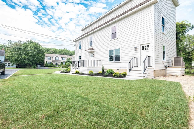 rear view of house featuring a lawn and central air condition unit