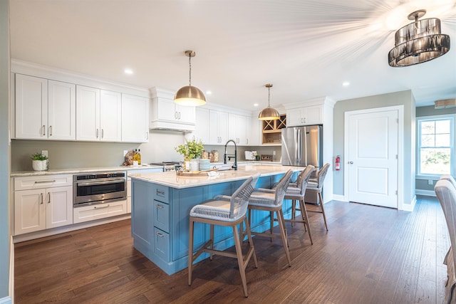 kitchen with a center island with sink, white cabinets, stainless steel appliances, and decorative light fixtures