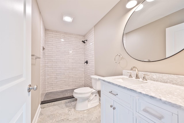 bathroom with tiled shower, vanity, and toilet