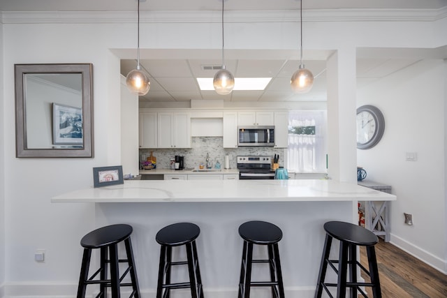 kitchen featuring a sink, a kitchen breakfast bar, backsplash, appliances with stainless steel finishes, and a peninsula