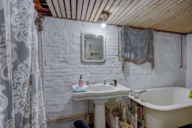 bathroom with brick wall and a tub