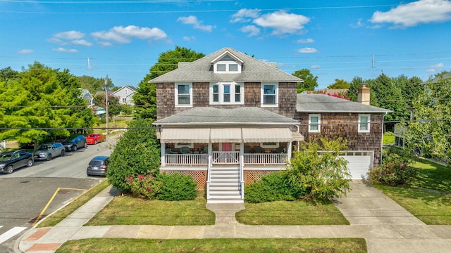 view of front of property featuring a garage, covered porch, and a front yard