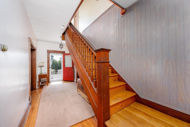 stairs with hardwood / wood-style flooring and wooden walls