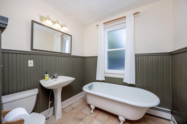 bathroom with a bath, sink, toilet, and baseboard heating