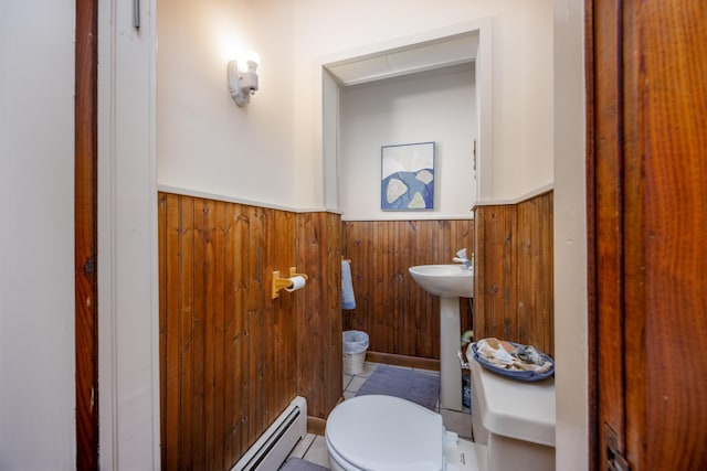 bathroom with a baseboard heating unit, wooden walls, sink, and toilet