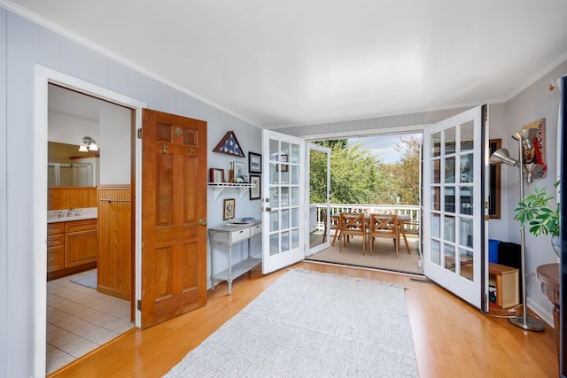 doorway featuring sink, ornamental molding, french doors, and light wood-type flooring