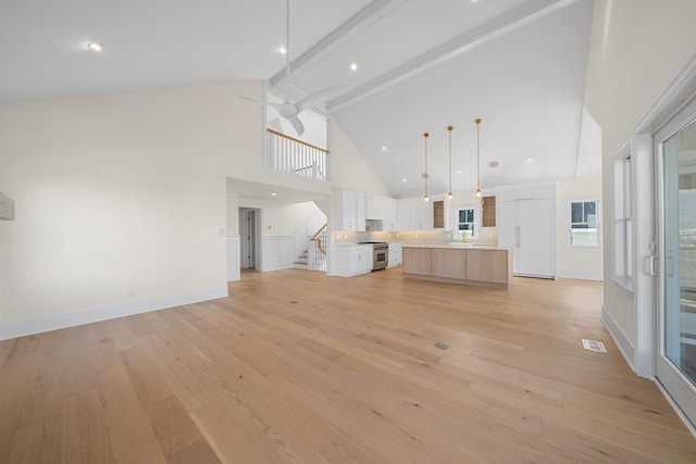 188 34th St, Avalon, NJ 08202 - unfurnished living room with high vaulted ceiling, beam ceiling, stairs, a ceiling fan, and light wood finished floors