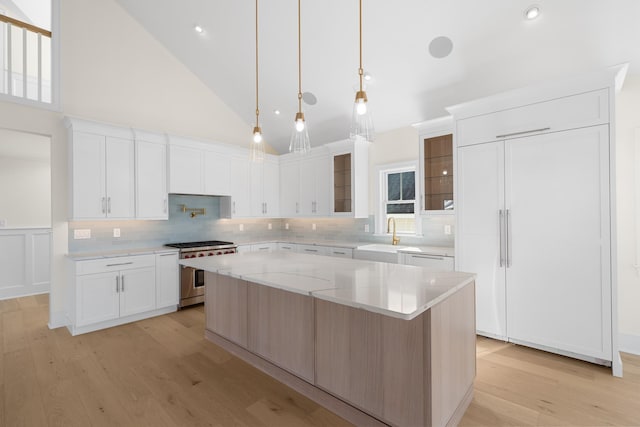 188 34th St, Avalon, NJ 08202 - kitchen featuring high quality appliances, light wood-type flooring, a center island, backsplash, and glass insert cabinets