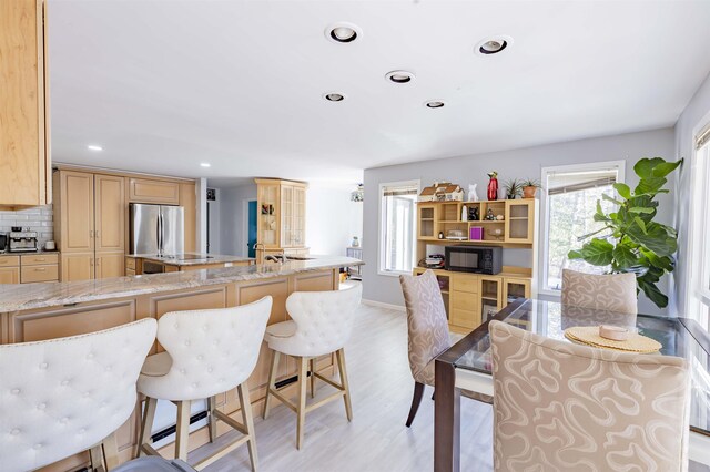 6 Rabbit Run, North Cape May, NJ 08204 - kitchen with tasteful backsplash, freestanding refrigerator, a kitchen breakfast bar, light wood-style flooring, and black microwave