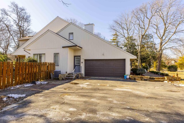 6 Rabbit Run, North Cape May, NJ 08204 - view of front facade with a chimney, fence, an attached garage, central AC unit, and aphalt driveway