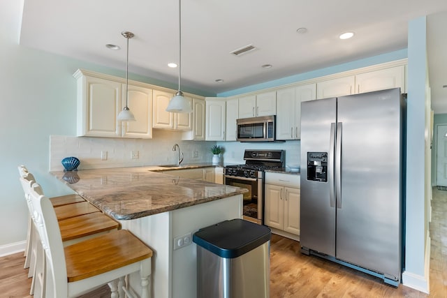 415 E Heather Rd Unit 105, Wildwood Crest, NJ 08260 - kitchen with appliances with stainless steel finishes, a peninsula, a kitchen breakfast bar, dark stone countertops, and a sink