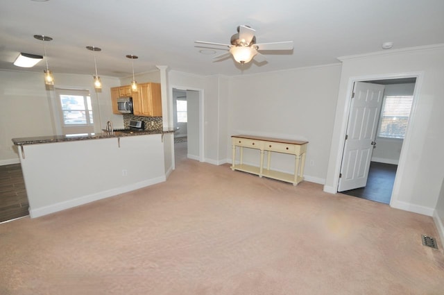 kitchen featuring kitchen peninsula, pendant lighting, tasteful backsplash, crown molding, and light carpet