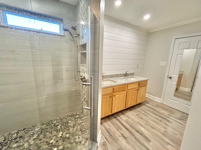 bathroom featuring wood-type flooring, vanity, a shower with shower door, and crown molding