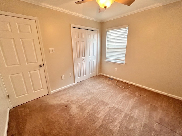 unfurnished bedroom featuring carpet flooring, a closet, ceiling fan, and crown molding