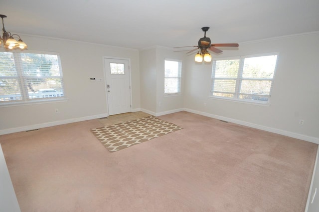 entrance foyer with ceiling fan with notable chandelier, ornamental molding, and light colored carpet