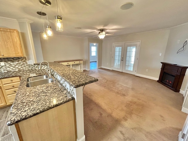 kitchen featuring kitchen peninsula, pendant lighting, light brown cabinetry, sink, and tasteful backsplash