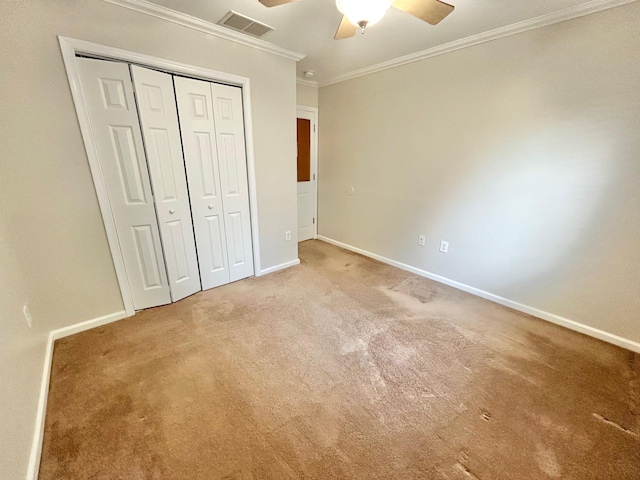 unfurnished bedroom with a closet, ornamental molding, ceiling fan, and carpet flooring