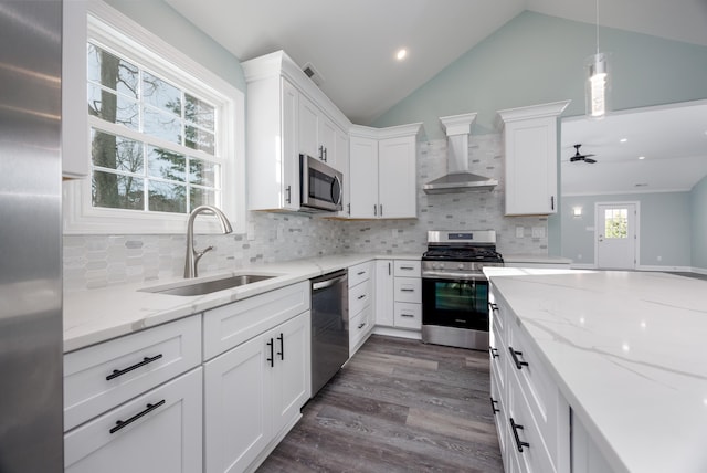 kitchen with ceiling fan, sink, wall chimney exhaust hood, stainless steel appliances, and white cabinets