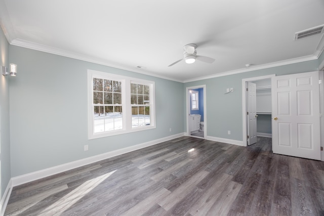 unfurnished bedroom with a walk in closet, a closet, ceiling fan, and ornamental molding