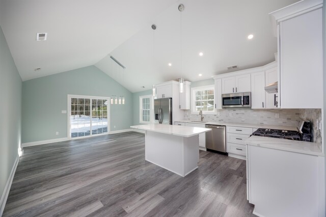 kitchen with appliances with stainless steel finishes, sink, a center island, white cabinetry, and hanging light fixtures