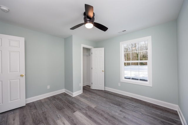 unfurnished bedroom with ceiling fan, dark hardwood / wood-style floors, and a closet