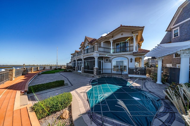 rear view of house featuring a balcony and a covered pool