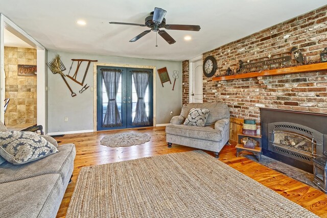 living area featuring french doors, baseboards, wood finished floors, and a fireplace with flush hearth