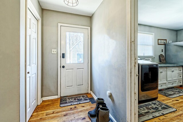 entryway with wood finished floors, washer / clothes dryer, and baseboards
