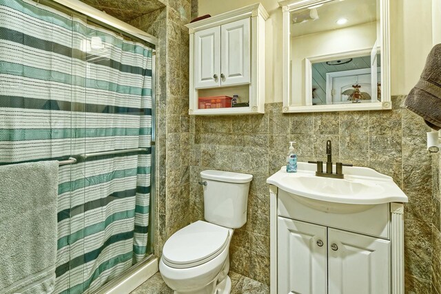 bathroom featuring curtained shower, toilet, vanity, and tile walls