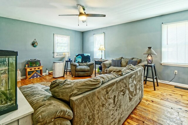 living area featuring visible vents, ceiling fan, wood finished floors, and baseboards