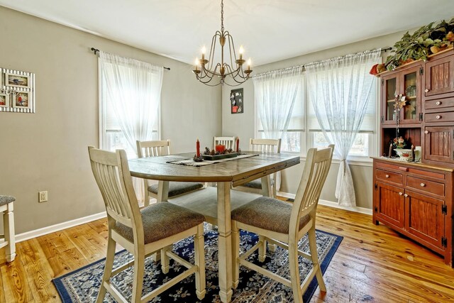 dining space with light wood-style floors, a notable chandelier, and baseboards