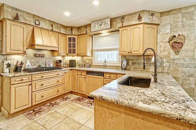 kitchen featuring light stone counters, a sink, light brown cabinets, premium range hood, and paneled dishwasher
