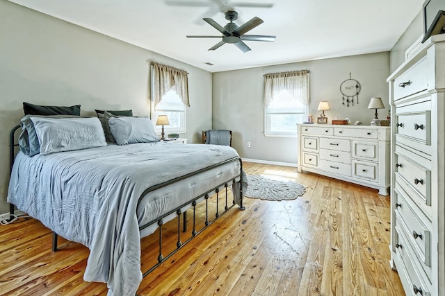 bedroom with baseboards, a ceiling fan, visible vents, and light wood-style flooring
