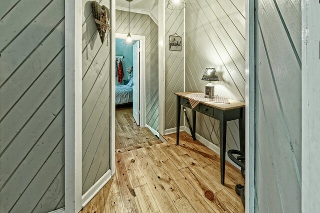 hall featuring wooden walls, hardwood / wood-style flooring, and baseboards
